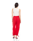 Woman wearing red Charo Cargo Pants with ankle drawstrings and side cargo pocket, paired with white sleeveless top.