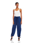 Woman wearing navy blue Charo Cargo Pants with ankle drawstrings and front and side pockets styled with white tank top and black sandals