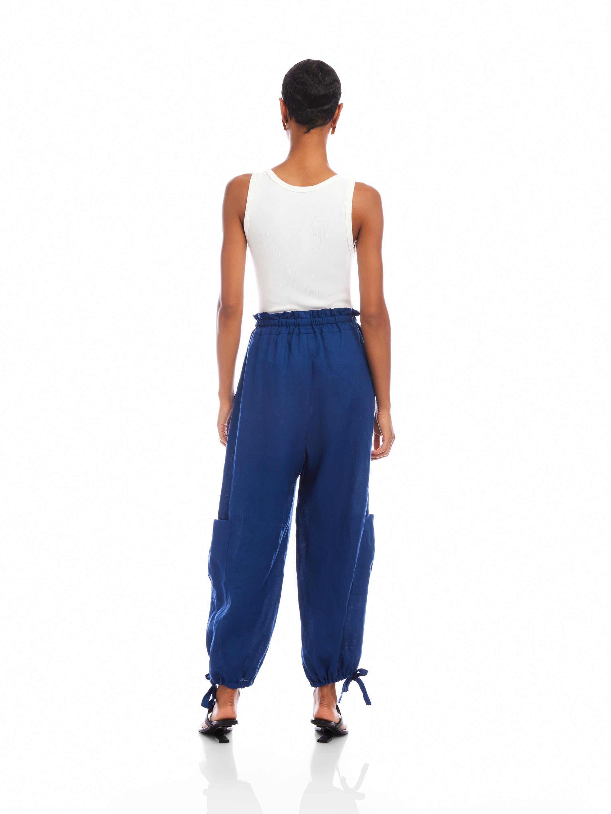 Woman wearing navy blue Charo Cargo Pants with ankle drawstrings and front and side cargo pockets viewed from the back