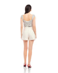 Woman wearing Cassidy Pleated Shorts in light beige with striped sleeveless top and red heels, back view
