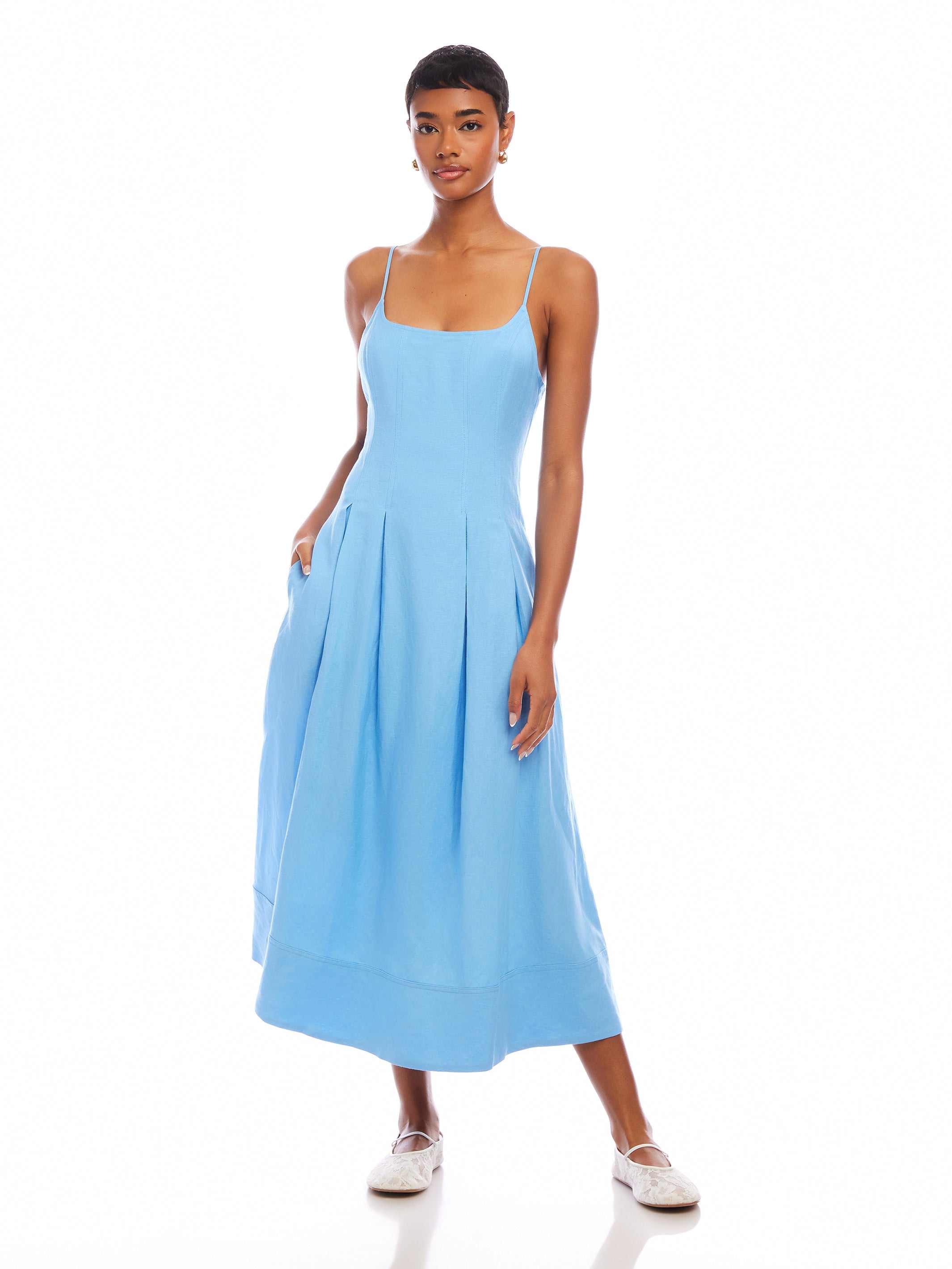 Woman wearing light blue Jessa Midi Dress with adjustable straps and side pockets, sleeveless with scoop neck design.