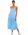 Woman wearing light blue Jessa Midi Dress with adjustable straps and side pockets, sleeveless with scoop neck design.