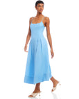Woman wearing light blue Jessa Midi Dress with adjustable straps and scoop neck, featuring a flowy, sleeveless design and side pockets.