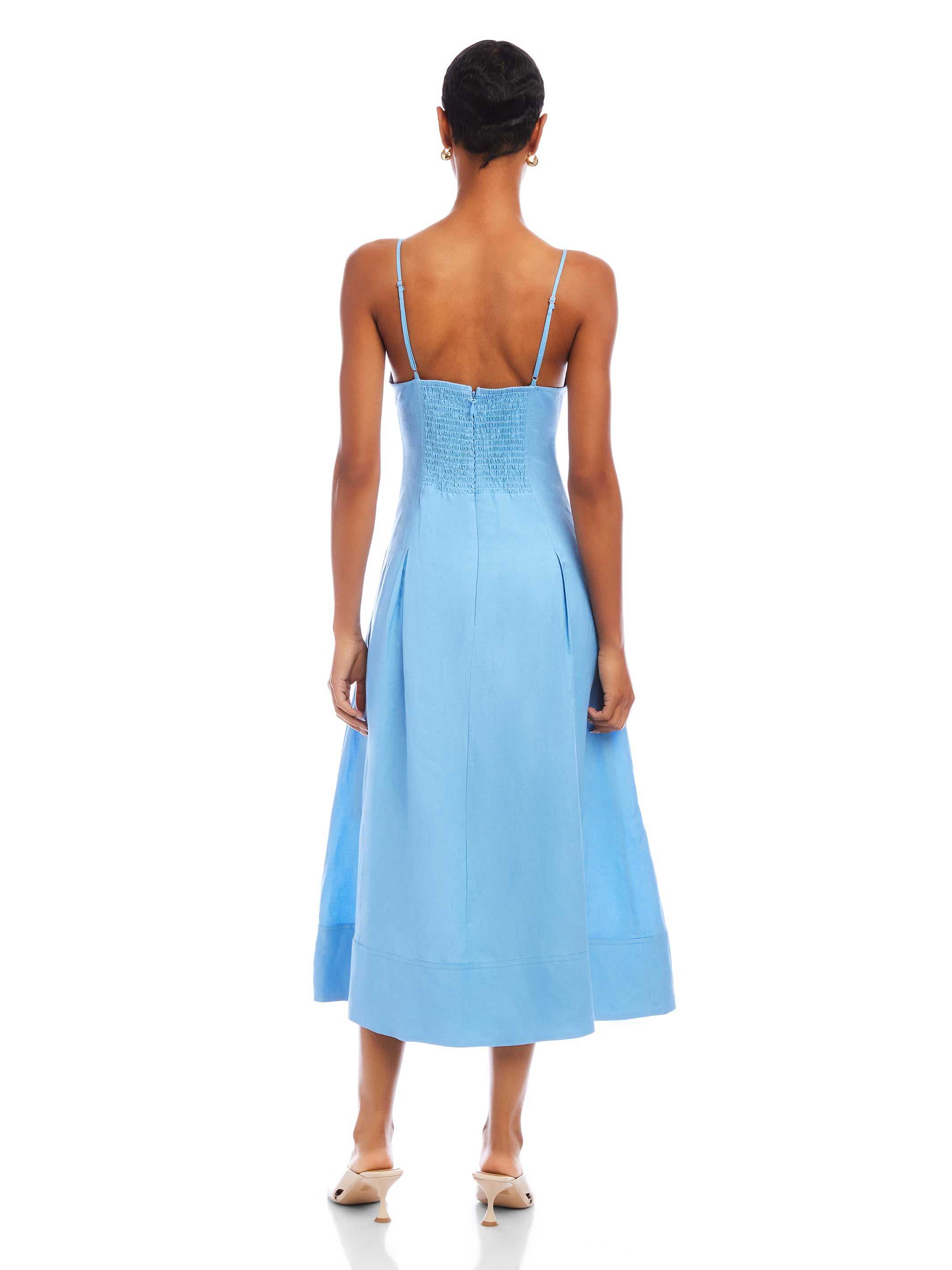 Back view of a woman wearing a blue Jessa Midi Dress with adjustable straps and a flowy midi-length hem.