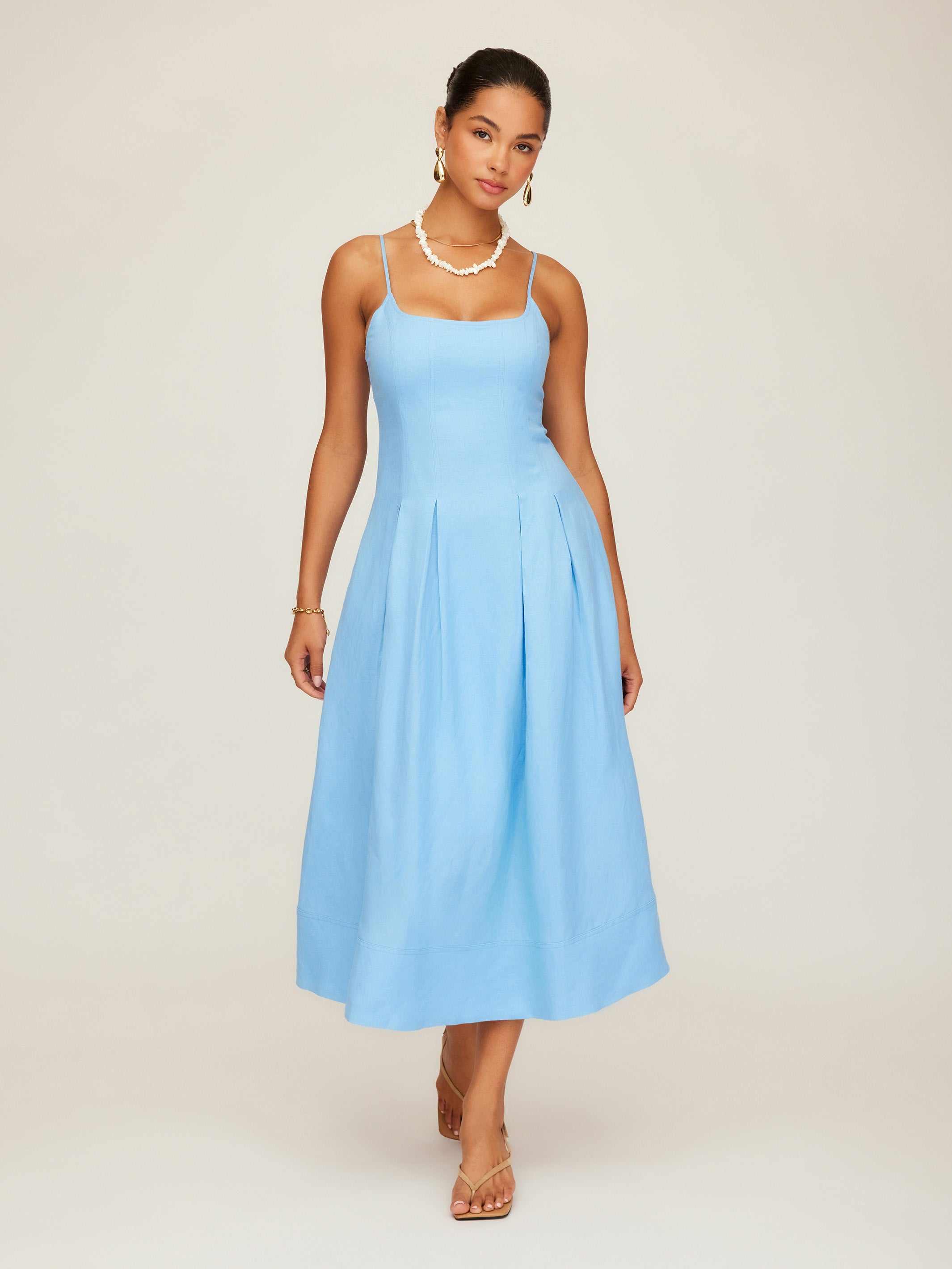 Woman wearing light blue sleeveless Jessa Midi Dress with adjustable straps and side pockets.