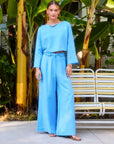 Woman wearing a blue Junie Flared Long Sleeve Top with flare sleeves and boat neck paired with matching wide-leg pants outdoors.