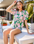 woman wearing green and pink floral button-up puff blouse with short sleeves and scoop neck sitting outdoors