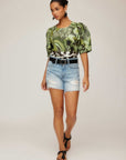 Green floral puff sleeve blouse with pleated voluminous sleeves and scoop neck worn with denim shorts