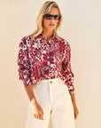 Lena Shirt in cream cotton with a bold red floral print, featuring a pointed collar, button front, and long sleeves.