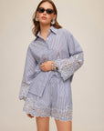Dakota Embroidered Shirt in blue-and-white pinstripe cotton, with a collared button front and scalloped lace embroidery at cuffs and hem.