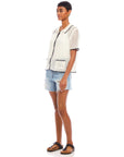 Woman wearing a white Gemma Crochet Shirt with contrasting black trim, boxy silhouette, short sleeves, front pockets, and scalloped edges.