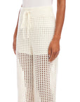 White Gianna crochet pants with wide leg, drawstring waist, and scalloped edges, made from cotton-acrylic blend yarn.