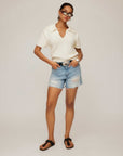 Woman wearing white Evie Knit Polo Top with short sleeves and collar paired with denim shorts and sandals
