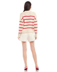 Back view of a woman wearing a beige Luca Crewneck Sweater with red horizontal stripes and a loose, oversized fit.