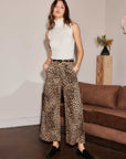 Woman wearing leopard print wide-leg cropped Rylee Cropped Pants with sleeveless white turtleneck and black shoes indoors