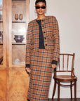Woman wearing Jackie Micro Jacket and matching plaid skirt with button-down front and collarless neckline