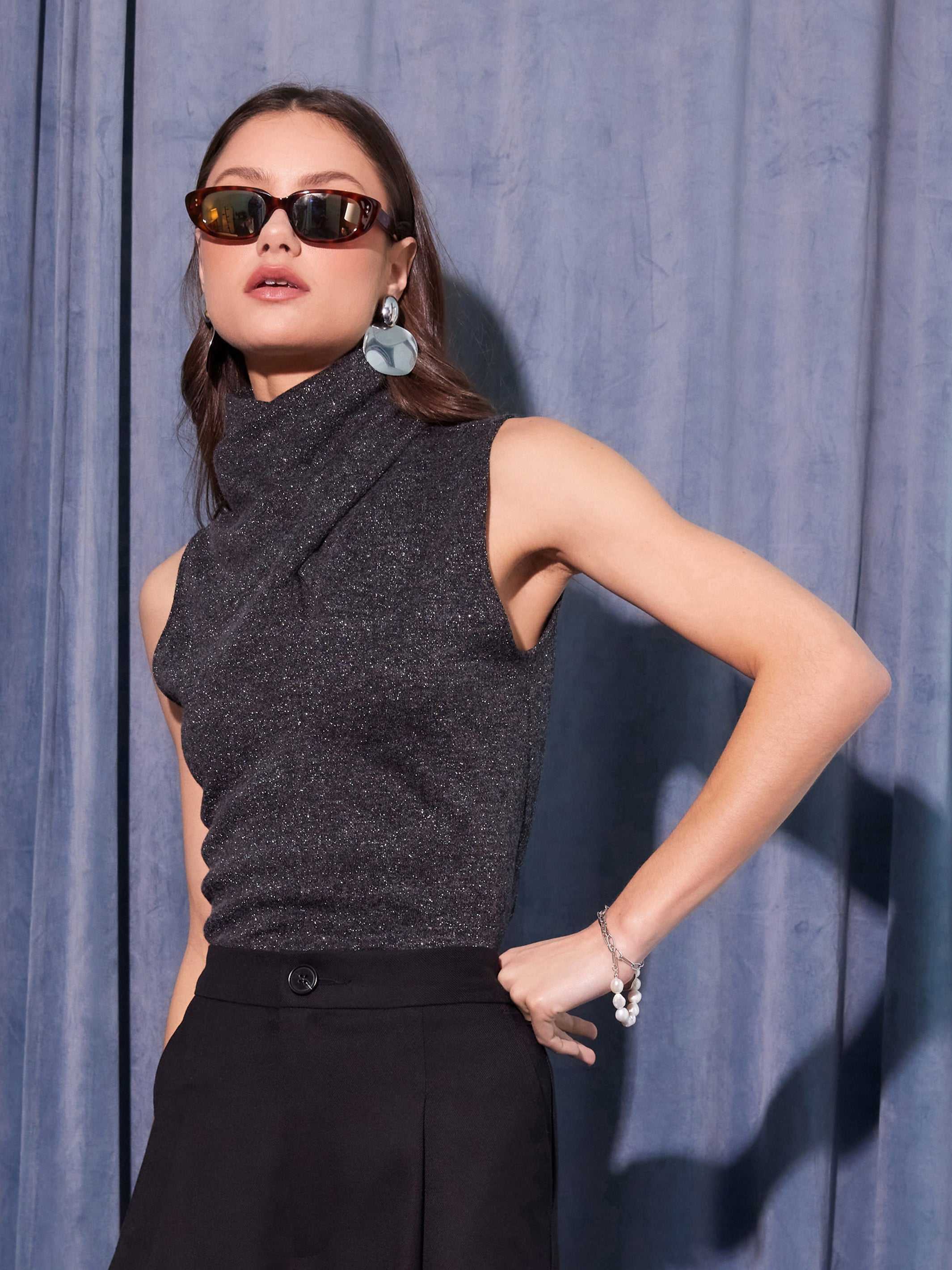Sleeveless metallic knit Abbey Turtleneck with high collar in dark gray worn with black pants