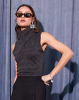Sleeveless metallic knit Abbey Turtleneck with high collar in dark gray worn with black pants