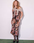 woman wearing a Mia Bias Midi Skirt with Byzantine print cupro fabric, styled with a beige sweater draped over shoulders and black heels