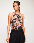 Woman wearing a Sicilie Tank with halter neckline and Byzantine print cupro fabric paired with black pants
