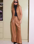 Woman wearing high-waist wide leg Sadie Trousers in shiny gold foil woven twill with front pleats and button closure.