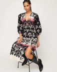 Woman wearing a Lizbeth Shirred Waist Dress with Italian damask block print, V-neck, 3/4 bishop sleeves, side slit, and pockets.