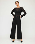Black Loren Scoop Back Top in sheer scalloped stretch lace with long flare sleeves and boatneck front worn with black wide-leg pants