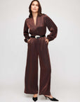 Women wearing a shimmering Skyler Jumpsuit with long blouson sleeves and V-neck, styled with heels