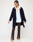 Woman wearing brown Harlow Bootcut Pants with front slits, white blouse, and navy coat