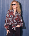 Woman wearing scarlet tie-front top with black and white floral print and long blouson sleeves