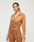 Woman wearing a brown Arabella Shirred Top with collared V-neck and cuffed long sleeves.
