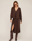 Woman wearing Brielle Midi Skirt in brown cupro fabric with side slit and elastic waist paired with matching top and brown boots