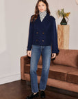 Woman wearing Abbey Turtleneck Tank with navy jacket and jeans indoors next to sofa and plant