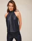 Woman wearing navy blue Alexis Halter Top made of smooth faux leather with high neckline and sleeveless design