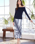 Woman wearing Mia Bias Midi Skirt with navy and light blue mixed bandana print and off-shoulder navy top in bright room