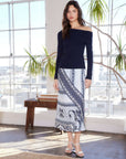 Woman wearing Ashley Asymmetric One-Shoulder Top in navy rib knit with long sleeves and side shirring paired with patterned midi skirt