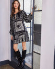 Woman wearing Stella Mini Dress with monotone paisley scarf print, long sleeves, and tie-front neck detail.