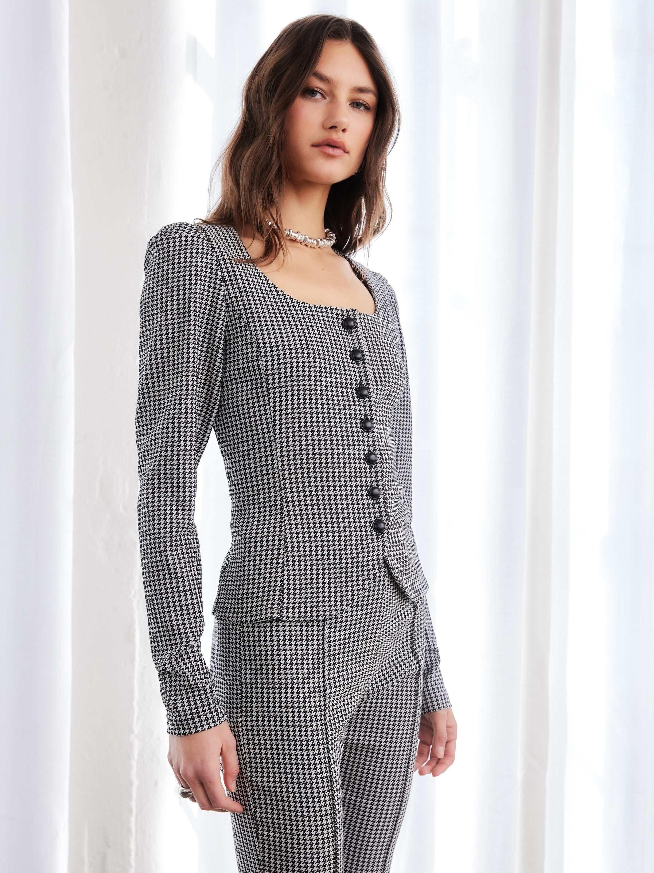Woman wearing structured houndstooth puff sleeve top with square neckline and button down closure