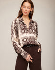 Woman wearing Tess Half Placket Shirt with earthy block print and long sleeves tucked into dark pants