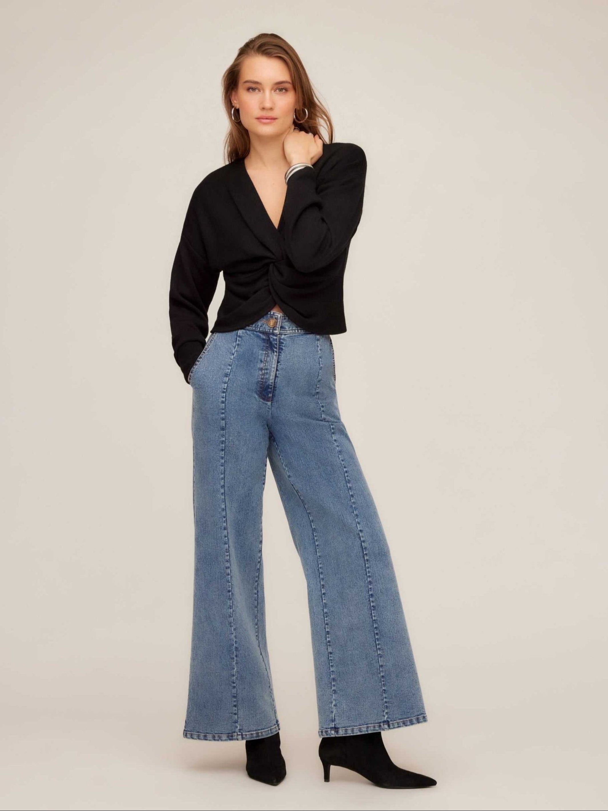 Woman wearing high-rise wide-leg Kristen Denim Trouser with front seaming and side pockets paired with black top and ankle boots