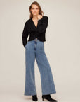 Woman wearing high-rise wide-leg Kristen Denim Trouser with front seaming and side pockets paired with black top and ankle boots