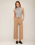 Woman wearing off white and black striped Abbey Turtleneck Tank with puckered stripe knit and sleeveless draped neckline paired with beige wide-leg pants and black loafers