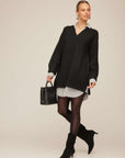 Carrie Mixed Media Sweater Dress in black knit with a white collared shirt layer, striped cuffs and shirttail hem, V-neck and long sleeves.
