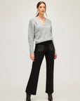 Woman wearing grey cozy v-neck sweater with long sleeves and black pants