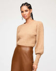 Woman wearing Lia Shirred Sleeve Sweater in camel color with long blouson sleeves and crew neck paired with brown leather skirt.