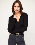 Woman wearing black Rory Sweater with V-neck and ribbed knit detail paired with jeans and black belt
