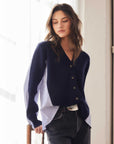 Woman wearing Celine Mixed Media cardigan with navy sweater front and striped white and blue woven shirt panels, styled with dark jeans.