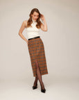 Woman wearing sleeveless fitted Kelli Turtleneck Sweater with plaid midi skirt and black heels