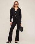 Woman wearing black Melanie Bootcut Pants with elastic waistband and mock fly paired with black cardigan and heels