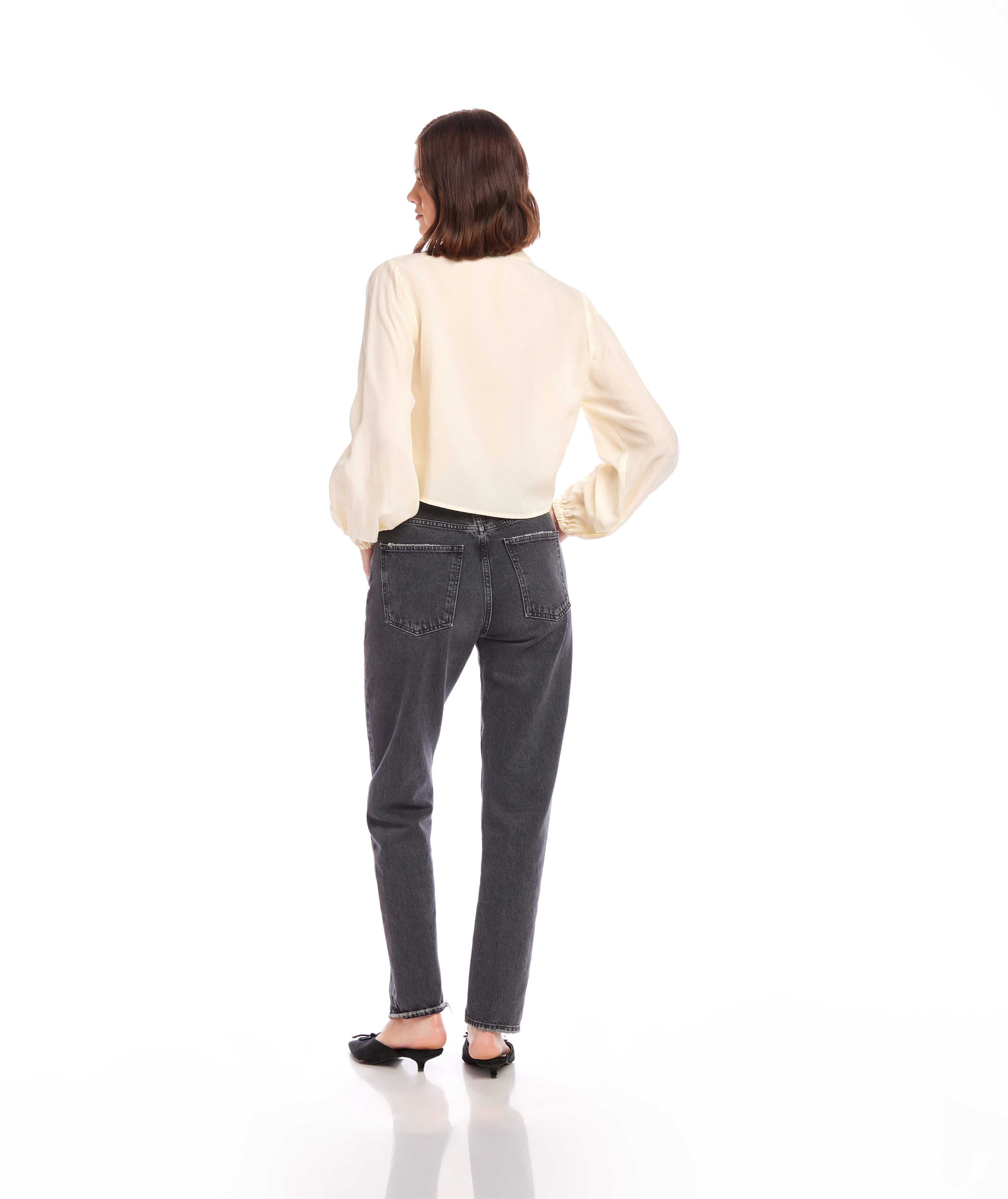 Woman wearing a cream Capri Tie-Front Blouse with long blouson sleeves and elasticized cuffs paired with dark high-waisted jeans, shown from the back.